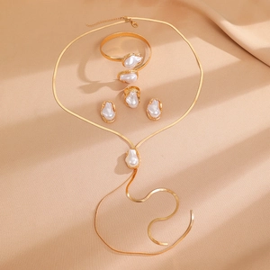 Baroque pearl jewelry set with gold necklace, bracelet, ring and earrings on beige cloth