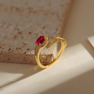 18K gold-plated snake ring with red heart gemstone and micro-pave crystals on stone background