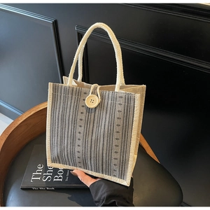 Detail of striped linen tote bag with wooden button closure and woven rope handle