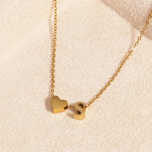 Close-up of a 18k gold plated heart and letter S pendant necklace on soft fabric