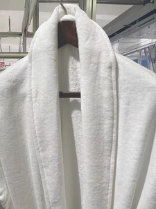 Detailed view of plush white cotton towel bathrobe fabric and thick shawl collar texture