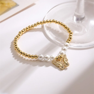 Detail of beaded bracelet with gold copper beads, white pearls, and a diamond butterfly charm