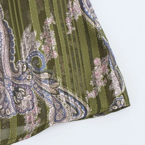 Detail of olive green fabric with gold metallic stripes and paisley floral patterns