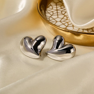 Polished silver heart stud earrings on elegant silk fabric background for women