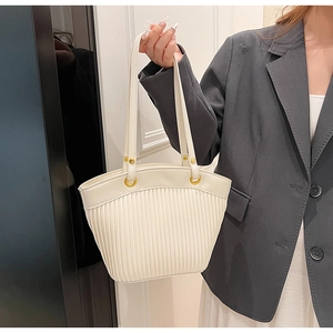 Detail of cream-white pleated tote bag with golden hardware and double shoulder straps