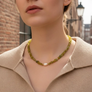 Detail of bohemian green crushed stone necklace with a central pearl on a casual model