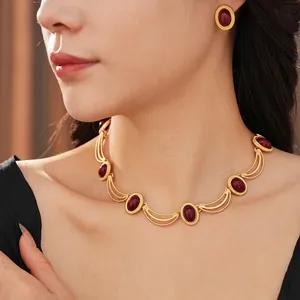 Vintage gold necklace and earring set with deep red oval gemstones on a female model