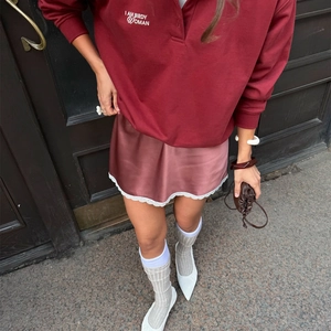 Détail de la mini-jupe en satin rose avec bordure en dentelle blanche et éclat soyeux