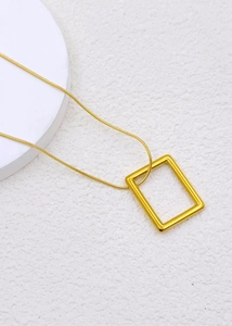 Macro view of gold minimalist rectangle pendant necklace with delicate snake chain