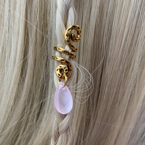 Detail of a gold hammered spiral dreadlock cuff with a pink teardrop crystal charm