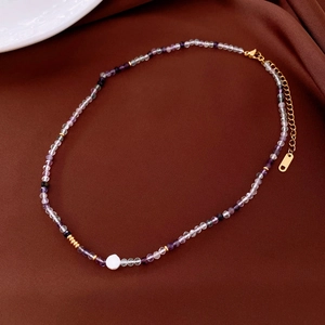 Close-up of beaded necklace with purple crystals, white pearl, and gold lobster clasp