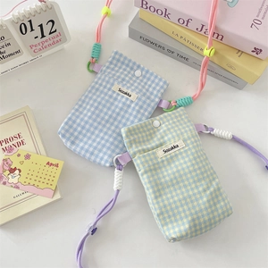 Detail of checkered fabric phone pouch with woven strap and secure magnetic closure