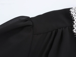 Close-up of black chiffon fabric with white lace trim and intricate hollow stitching