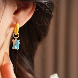 Close-up of model wearing cute light blue enamel elephant drop earrings with yellow hoop