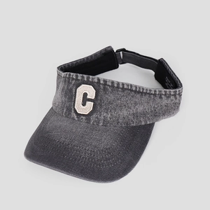 Detail of grey denim sun visor featuring a textured cream letter C embroidery patch