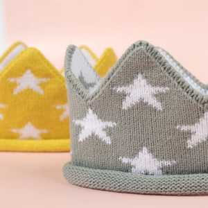 Gros plan de bonnets couronne tricotés pour bébé en gris et jaune avec étoiles