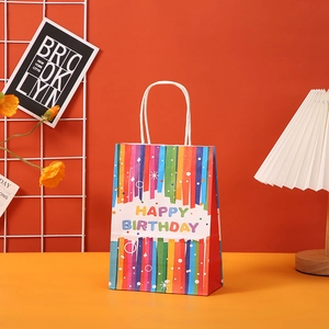 Detailed view of rainbow striped birthday gift bag with white rope handles and festive text