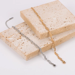 Detail of wavy textured stainless steel bracelets in gold and silver on stone decor