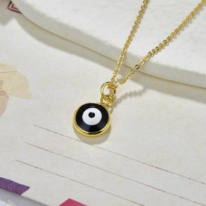 Detailed macro view of a gold Evil Eye circular pendant with enamel finish and chain