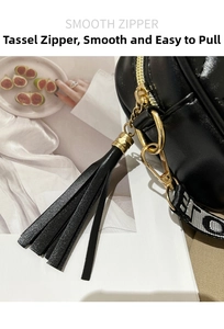 Detail of black glossy leather bag with gold ring buckle and jacquard letter strap