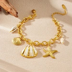 Gold-plated stainless steel marine bracelet with starfish and shell charms on beach sand