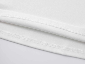 Gros plan détaillé montrant les coutures doubles professionnelles sur l'ourlet du T-shirt blanc