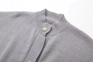 Detail der grauen Strickjacke mit goldgeprägten Knöpfen und Stehkragen-Texturansicht