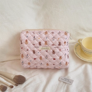 Detailed view of pink quilted fabric cosmetic bag with cute bear pattern and zipper