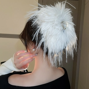 Detail view of white feather hair claw clip on a woman's bun for an elegant hairstyle