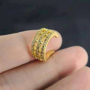 Macro shot of gold three-row zircon non-piercing cartilage ear cuff held by hand