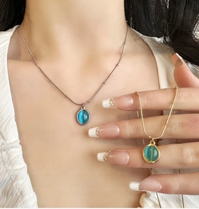 Macro shot of oval blue cat eye stone pendant with vintage gold and silver bead chain