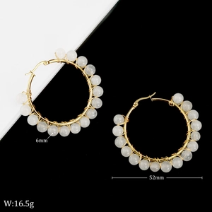 Detail view of 52mm gold hoop earrings with white natural stone beads and wire wrap
