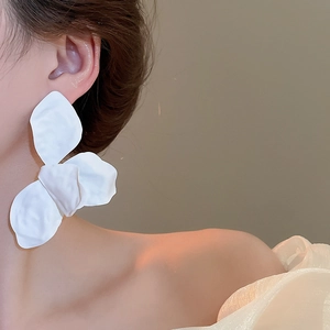 Close-up of elegant white oversized flower earrings with matte finish on a female model