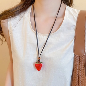 Detailed close-up of a vibrant red resin strawberry pendant with green leaf on a necklace