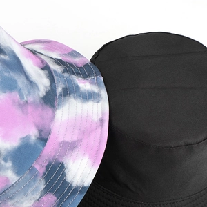 Close-up of tie-dye and solid black reversible bucket hats with reinforced stitching