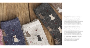 Detailed close-up of wool-blend knit socks featuring cute cat and heart patterns