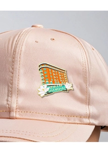 Detail of metal Wukang Mansion pin on a pink cap, featuring Shanghai souvenir design