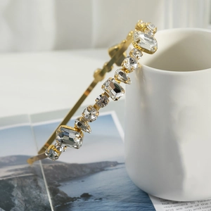 Detail of crystal headband with emerald and pear-cut stones on gold metal base