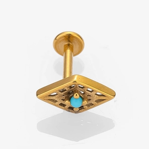 Detailed close-up of golden stainless steel piercing with hollow flower and turquoise stone