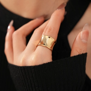 Polished gold wide open ring featuring a smooth curved surface on a female hand