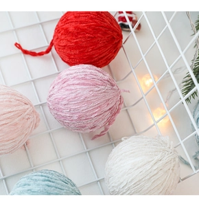 Detail of colorful 6cm wool felt Christmas balls in a white basket with festive lights