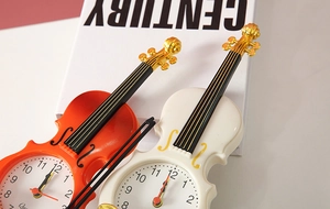 Dettaglio di sveglie a forma di violino arancione e crema con accenti decorativi dorati