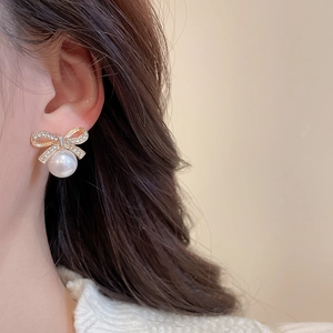 Detailed view of elegant bow knot earrings with white pearls and sparkling crystals