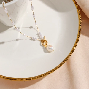 Detailed macro view of gold-plated 18K OT buckle with a white baroque pearl pendant