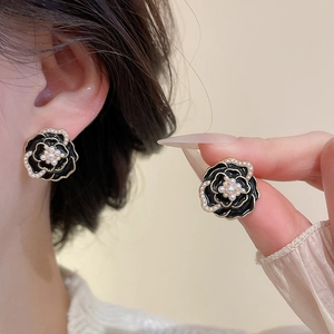 Close-up of elegant camellia earrings with black petals and white pearl centers