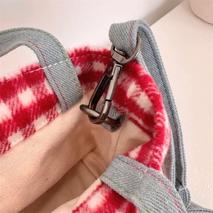Close-up of red and white plaid wool tote with gray denim strap and metallic swivel hook