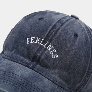 Macro shot of Feelings white embroidery on washed navy denim fabric of a baseball cap