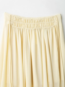 Close-up of light yellow skirt featuring elastic pleated waist and soft chiffon fabric