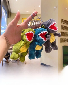 Close-up of soft plush Tyrannosaurus keychains in green, blue, and gray colors