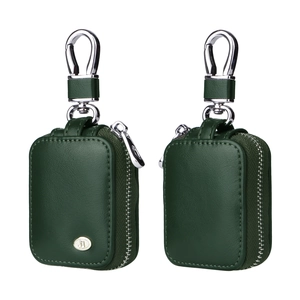 Detail view of dark green leather AirPods cases featuring gold logo and silver metal hooks